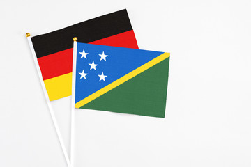 Solomon Islands and Germany stick flags on white background. High quality fabric, miniature national flag. Peaceful global concept.White floor for copy space.