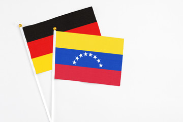 Venezuela and Germany stick flags on white background. High quality fabric, miniature national flag. Peaceful global concept.White floor for copy space.