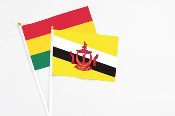 Brunei and Ghana stick flags on white background. High quality fabric, miniature national flag. Peaceful global concept.White floor for copy space.
