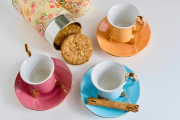 Set of vintage colorful cups of tea with cookies and cinammon close-up. Infusion, breakfast and morning concept.