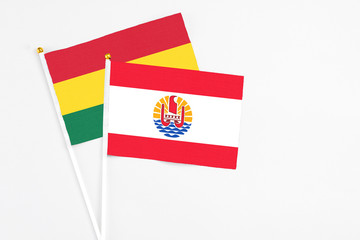 French Polynesia and Ghana stick flags on white background. High quality fabric, miniature national flag. Peaceful global concept.White floor for copy space.