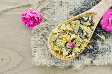 Assortment of dry flower tea in spoon on wooden background