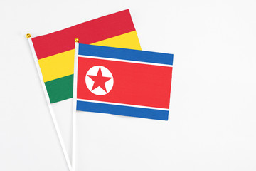 North Korea and Ghana stick flags on white background. High quality fabric, miniature national flag. Peaceful global concept.White floor for copy space.
