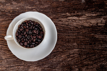 cup of coffee with beans on wooden table