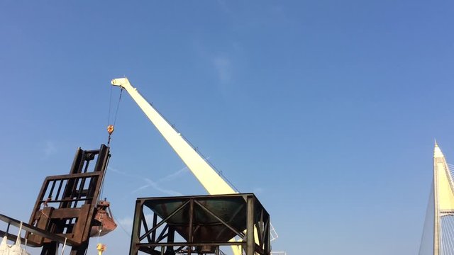 Large yellow scoop Are scooping the white Urea chemical fertilizer From a pontoon boat to unload