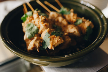 chicken skewers on wooden skewers in a green bowl closeup