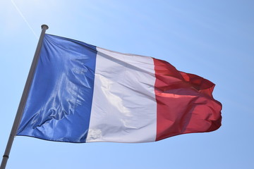 French flag on a sunny day with blue background.