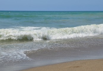 a white foaming wave runs over the sandy shore
