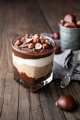 Layered dessert with chocolate mousse, cream cheese and whipped cream mixed with chestnut puree, topped with hazelnuts in a glass jar