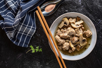 Soup with pieces of pork and mushrooms in bowl. View from above.