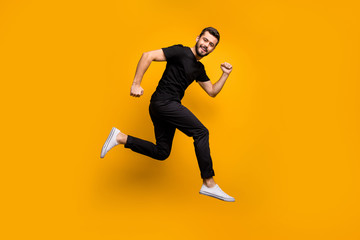 Fototapeta na wymiar Full body profile photo of handsome millennial guy jumping high rushing shopping mall best black friday offers season wear black t-shirt trousers isolated yellow color background