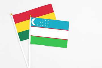 Uzbekistan and Ghana stick flags on white background. High quality fabric, miniature national flag. Peaceful global concept.White floor for copy space.