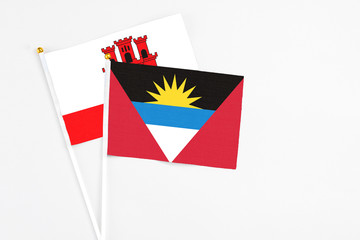 Antigua and Barbuda and Gibraltar stick flags on white background. High quality fabric, miniature national flag. Peaceful global concept.White floor for copy space.