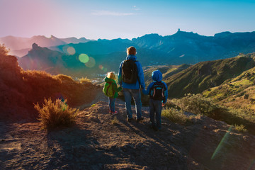Father with son and daughter travel in sunset mountains
