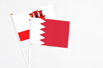 Bahrain and Gibraltar stick flags on white background. High quality fabric, miniature national flag. Peaceful global concept.White floor for copy space.