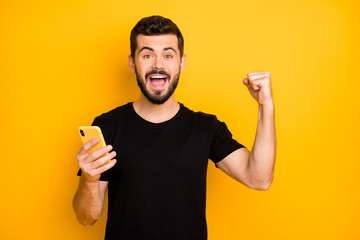 Portrait of cheerful bearded guy use internet on his smartphone win social media lottery scream...