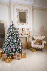 New Year tree with flowers and multicolored toys at the fireplace with chair