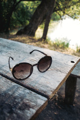 Fototapeta na wymiar Sun glasses lie on a wood table. Close up.