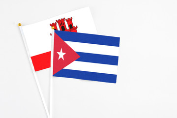 Cuba and Gibraltar stick flags on white background. High quality fabric, miniature national flag. Peaceful global concept.White floor for copy space.