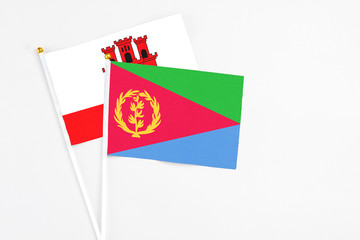 Eritrea and Gibraltar stick flags on white background. High quality fabric, miniature national flag. Peaceful global concept.White floor for copy space.