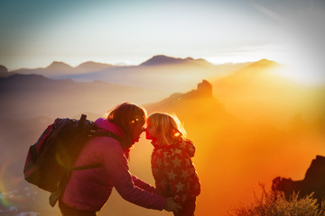 mother and little daughter travel in sunset mountains, family silhouette
