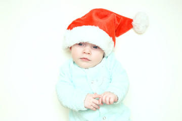 A newborn baby in a Christmas hat smiles cheerfully while lying in a crib at home. The concept of family happiness. Photo shoot of the baby for 4-5 months. merry Christmas