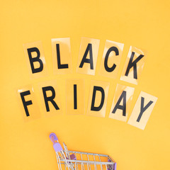 Wheelbarrow for shopping and the word black friday on orange background.