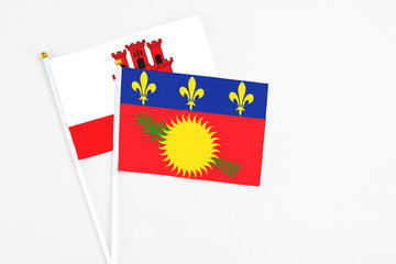 Guadeloupe and Gibraltar stick flags on white background. High quality fabric, miniature national flag. Peaceful global concept.White floor for copy space.