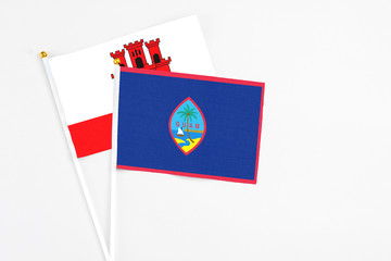 Guam and Gibraltar stick flags on white background. High quality fabric, miniature national flag. Peaceful global concept.White floor for copy space.