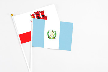Fototapeta na wymiar Guatemala and Gibraltar stick flags on white background. High quality fabric, miniature national flag. Peaceful global concept.White floor for copy space.