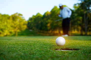 Blurred golfer playing golf in the evening golf course, on sun set evening time.