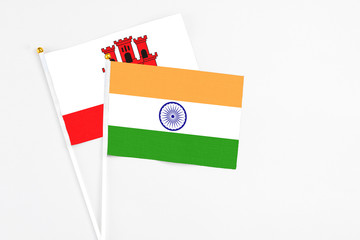 India and Gibraltar stick flags on white background. High quality fabric, miniature national flag. Peaceful global concept.White floor for copy space.