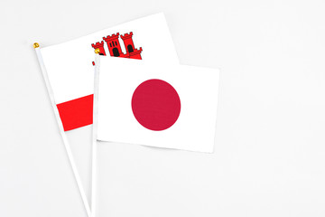 Japan and Gibraltar stick flags on white background. High quality fabric, miniature national flag. Peaceful global concept.White floor for copy space.