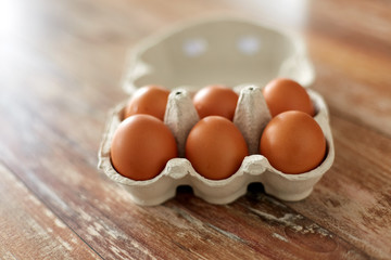 food, culinary and cooking concept - close up of natural chicken eggs in cardboard box on wooden table