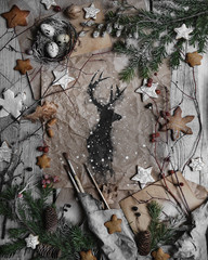  Still life of flatlay with Christmas gingerbreads and decorations top view on vintage textured paper background with a hand drawn of black deer with art elements close up