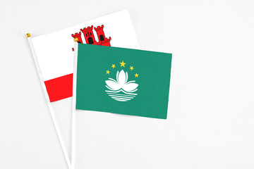 Macao and Gibraltar stick flags on white background. High quality fabric, miniature national flag. Peaceful global concept.White floor for copy space.