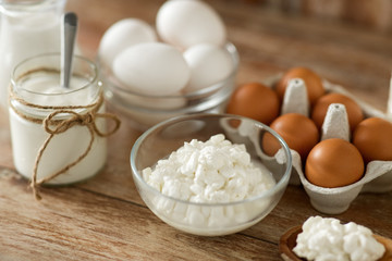 food and eating concept - close up of cottage cheese, jug of milk, homemade yogurt and chicken eggs on wooden table