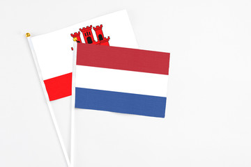 Netherlands and Gibraltar stick flags on white background. High quality fabric, miniature national flag. Peaceful global concept.White floor for copy space.