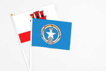 Northern Mariana Islands and Gibraltar stick flags on white background. High quality fabric, miniature national flag. Peaceful global concept.White floor for copy space.