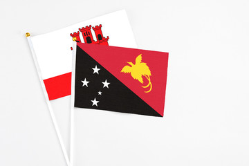 Papua New Guinea and Gibraltar stick flags on white background. High quality fabric, miniature national flag. Peaceful global concept.White floor for copy space.