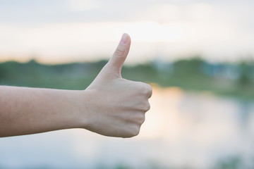 hand with thumb up on background of blue sky
