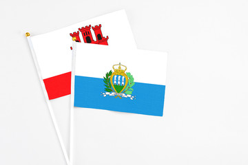 San Marino and Gibraltar stick flags on white background. High quality fabric, miniature national flag. Peaceful global concept.White floor for copy space.