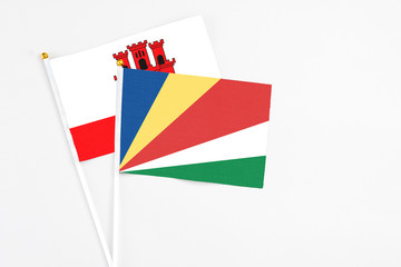 Seychelles and Gibraltar stick flags on white background. High quality fabric, miniature national flag. Peaceful global concept.White floor for copy space.