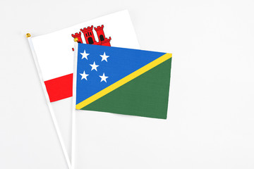 Solomon Islands and Gibraltar stick flags on white background. High quality fabric, miniature national flag. Peaceful global concept.White floor for copy space.