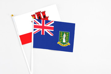 Fototapeta premium British Virgin Islands and Gibraltar stick flags on white background. High quality fabric, miniature national flag. Peaceful global concept.White floor for copy space.