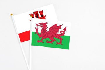 Wales and Gibraltar stick flags on white background. High quality fabric, miniature national flag. Peaceful global concept.White floor for copy space.