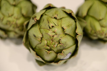 Close up of green artichokes sitting on marble