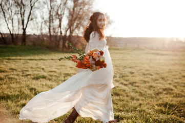 the bride is spinning in a light flying dress at sunset. focus on the wedding bouquet