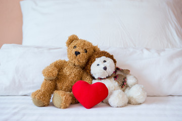 Two little teddy bear sitting on the bed with red heart, valentine concept background, relationship and love