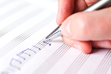 Hand writing music notes close-up
